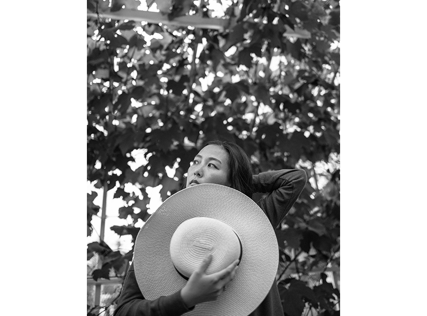 woman in greenhouse holding a hat